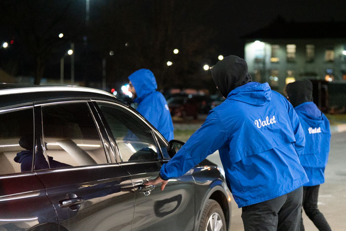 Valet attendants in blue jackets assisting a car at night, representing our established valet parking franchise network.
